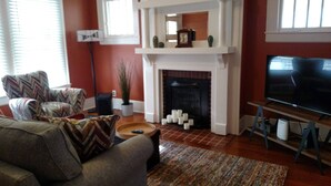 Una sala de estar con chimenea, televisor y sofá.