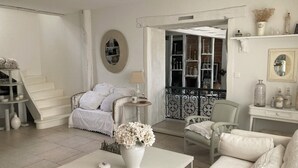 Un salón espacioso con un sofá blanco, una mesa de centro con un florero, una escalera y una estantería.