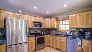 A kitchen with wooden cabinets, stainless steel appliances, a microwave, stove, oven, and dishwasher. - NEW! Valley View Mountain Getaway (Hiawassee)