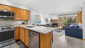 A modern kitchen with stainless steel appliances, wooden cabinets, and a large island. - 3BR | Whistler Creek Ridge | Ski-in/out | Private Hot Tub | Wood Fire | Private Garage (Whistler)