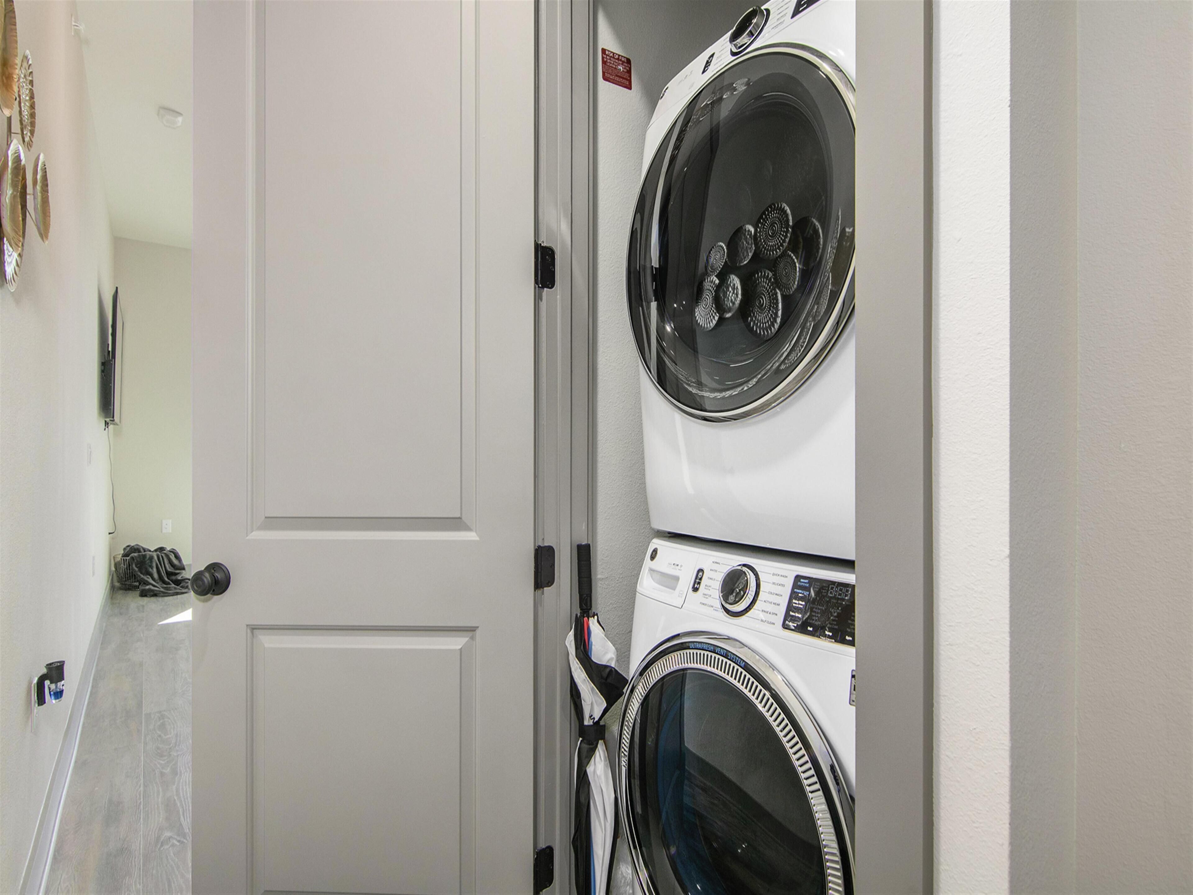 A laundry room with stacked washers and dryers, a door, and a towel rack.