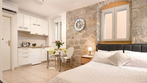 A bedroom with a large bed, a nightstand, and a wall clock. - Sun Spalato Giardino (Split)
