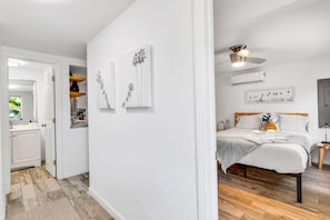 Een slaapkamer met een bed, nachtkastje en plafondventilator.