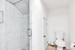 A modern bathroom with a shower, toilet, and sink.