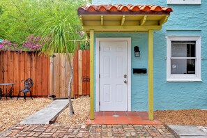 A house with a white door, a wooden fence, and a blue exterior wall.