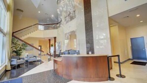 A spacious lobby with a reception desk, a staircase, and seating area.