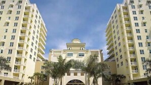 A multi-story hotel with a central courtyard, palm trees, and a fountain.