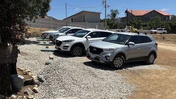 A parking area with several white SUVs parked on gravel.