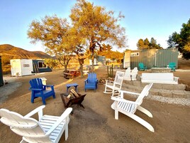 Un espacio al aire libre con sillas Adirondack, una fogata y un árbol.