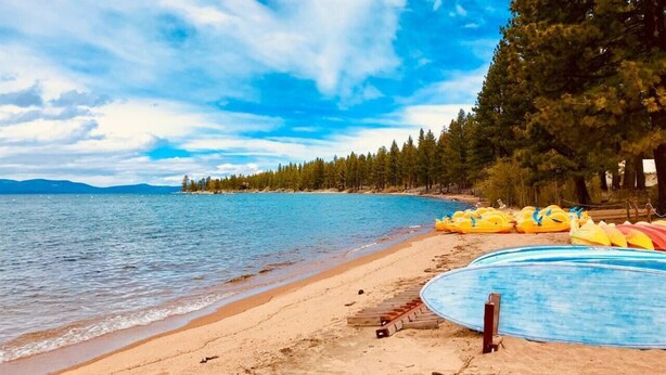 A beach with a swimming pool, kayaks, and a forested area in the background. - Short Walk 2Tahoe~Family~Beach~Kings Beach Retreat (Tahoe Vista)