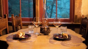 Una mesa de comedor con platos de comida, copas de vino y una botella de vino.