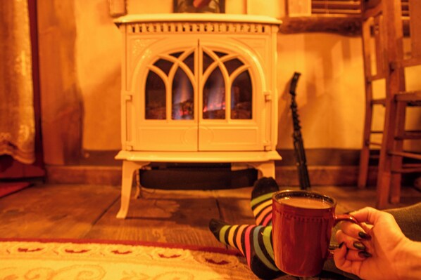 A cozy room with a fireplace, a wooden chair, and a person holding a mug.