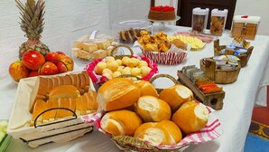 Une table de buffet proposant une variété d’aliments, notamment du pain, des pâtisseries et des fruits.