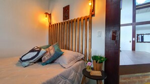 Une chambre à coucher comprenant un lit, des oreillers, une table de chevet, une lampe fixée au mur et une tête de lit en lattes de bois.