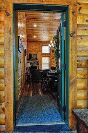 A wooden interior with a dining area, a fireplace, and a television. - Jackalopia: Hot Tub, Firepit & Mountain Folklore!" (Gatlinburg)