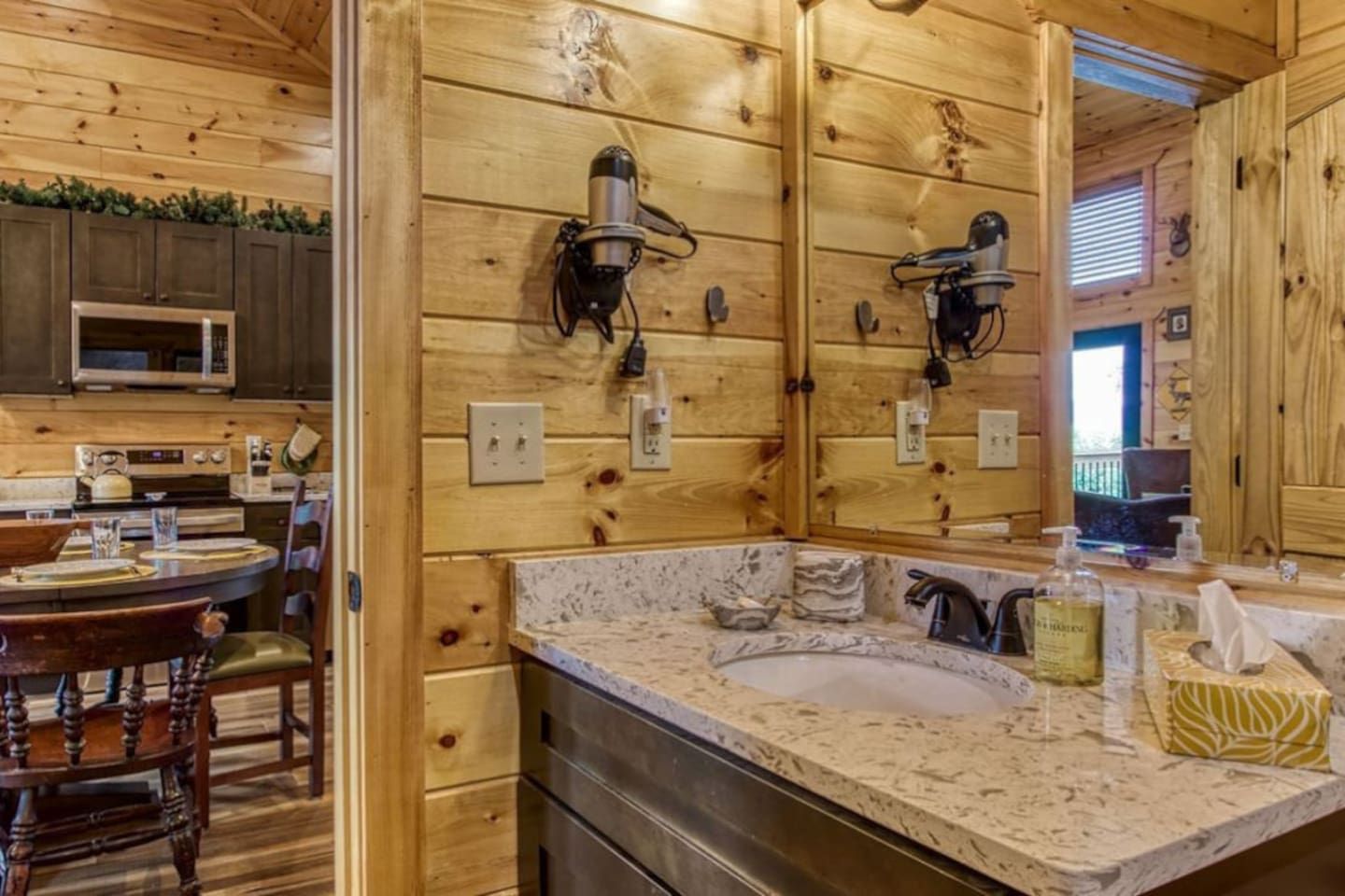 A wooden interior with a kitchen, dining area, and a bathroom with a sink and mirror.