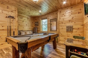 A wooden room with a pool table, a sofa, and a dartboard. - Jackalopia: Hot Tub, Firepit & Mountain Folklore!" (Gatlinburg)