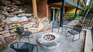 Eine Terrasse mit einem Steinkamin, umgeben von vier Metallstühlen.