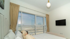 Ett hotellrum med en stor säng, beige gardiner, en platt-TV och utsikt över ett ökenlandskap.