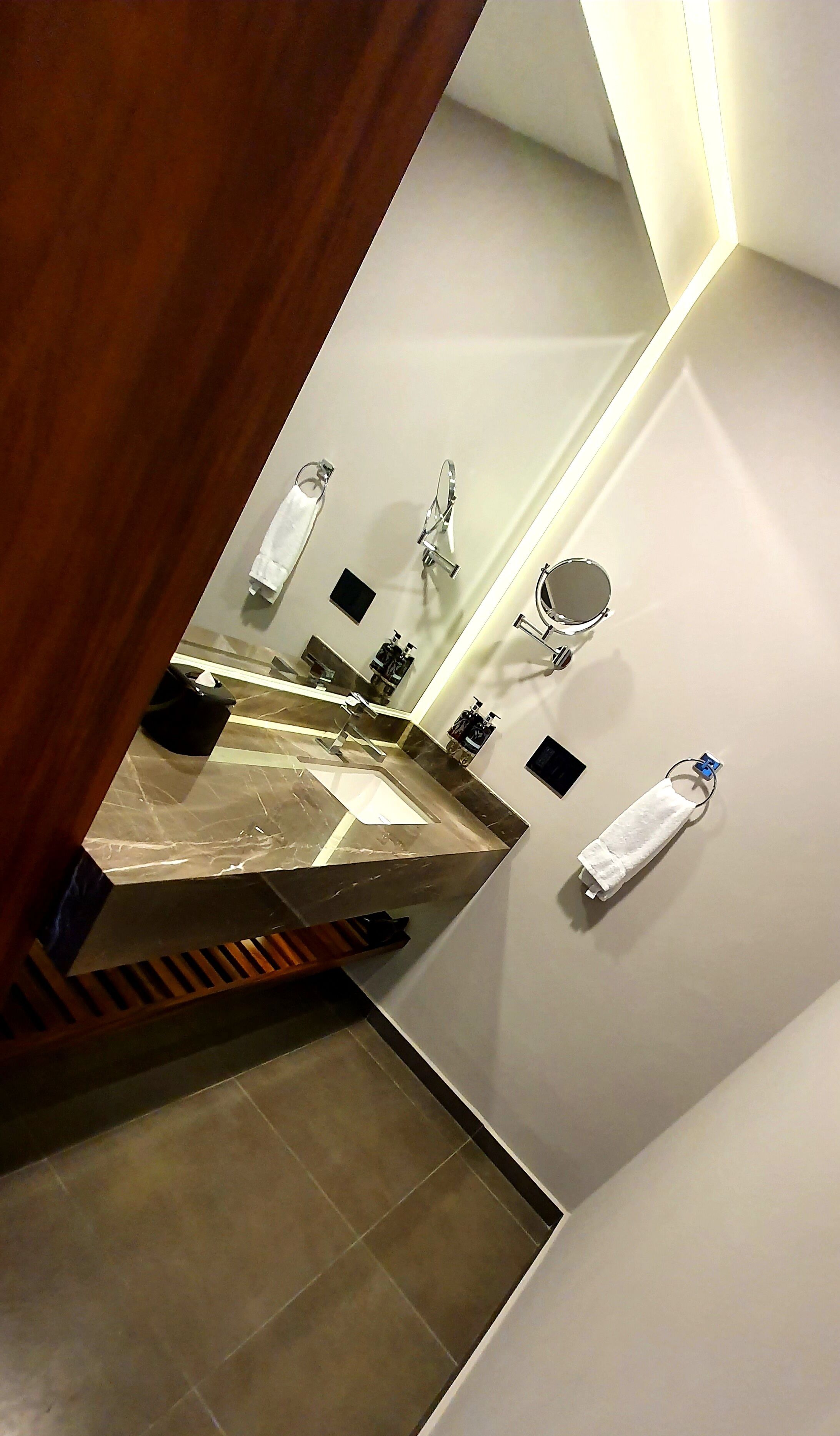A modern bathroom with a large mirror, a sink, and a toilet.
