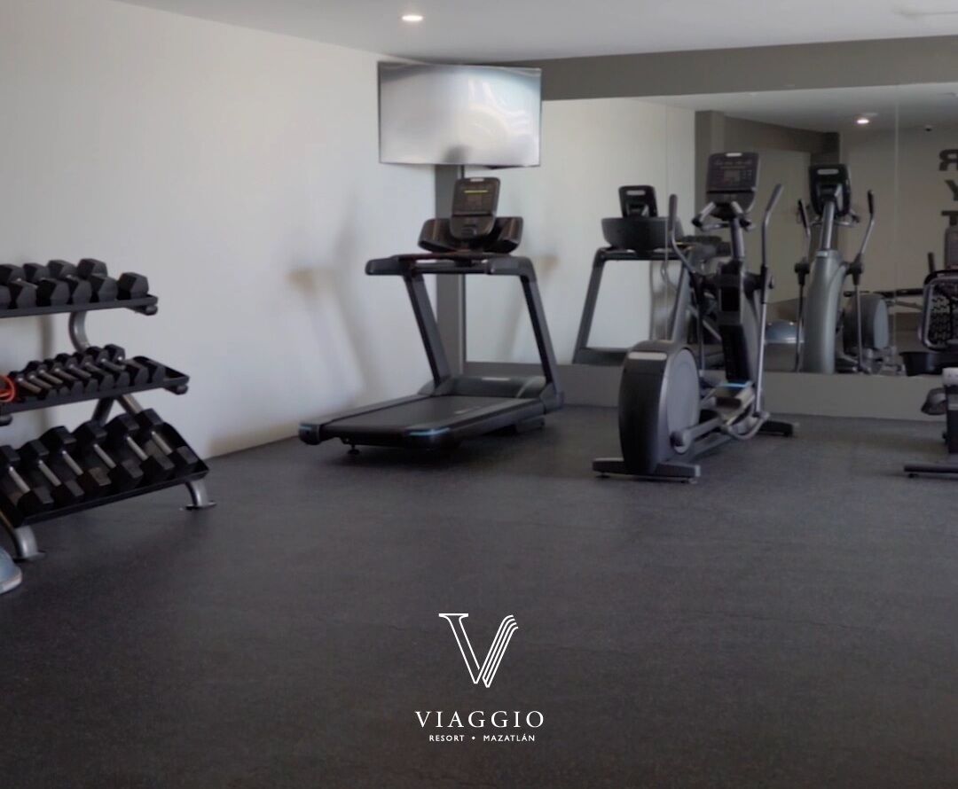 A gym with treadmills, elliptical machines, and dumbbells.