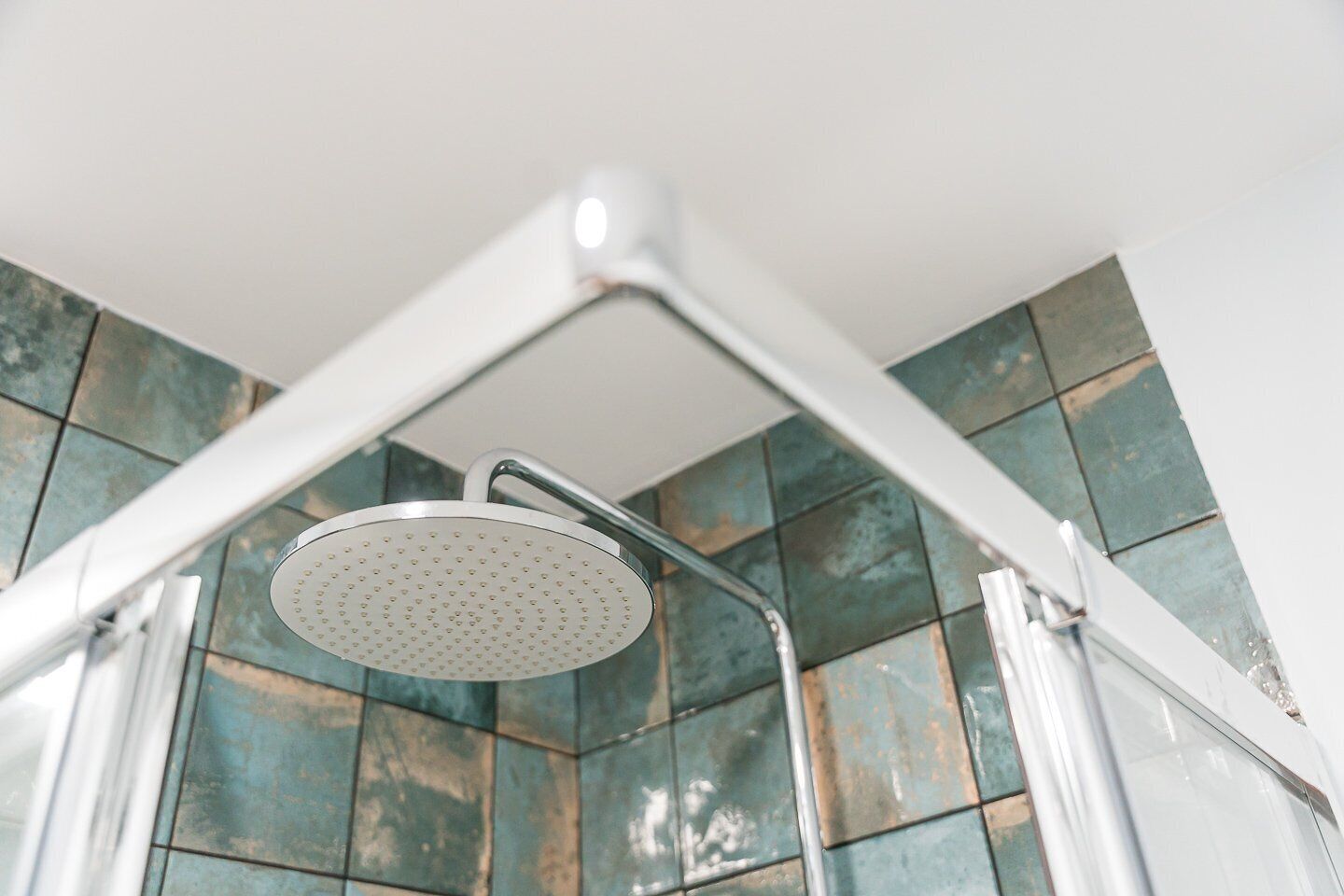 Eine Dusche mit modernem Design, ausgestattet mit einer runden Duschbrause und einem Chromrahmen.
