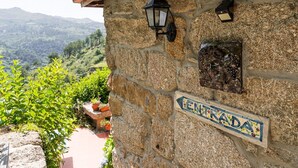 A stone building with a sign reading "ENTRADA" and a view of a mountainous landscape. - Casa Museu Rural Hotel (Cinfães)