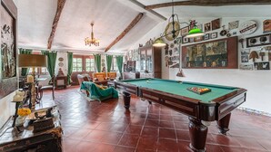 A spacious room with a pool table, green curtains, and a chandelier. - Casa Museu da Geada: Room 5 (Cinfães)