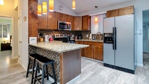 A modern kitchen with a central island, stainless steel appliances, and wooden cabinetry.