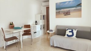 A minimalist room with a bed, a desk, and a chair. There is a beach scene painting on the wall. - Stunning & Intimate views. Terrace + Rooftop. Wifi (Tamariu)