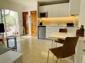 A modern kitchen with white cabinets, a built-in microwave, and a small refrigerator.