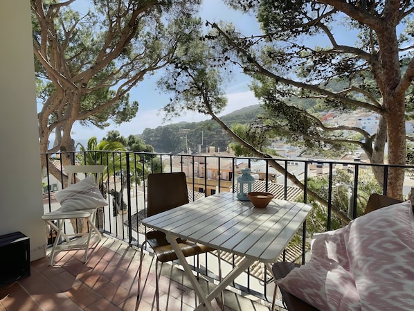 A balcony with a table and chairs, overlooking a cityscape.