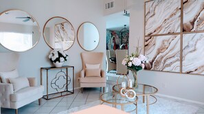 A modern living room with a sofa, armchair, round mirrors, and a glass coffee table. - Springs Tranquility. (Coral Springs)