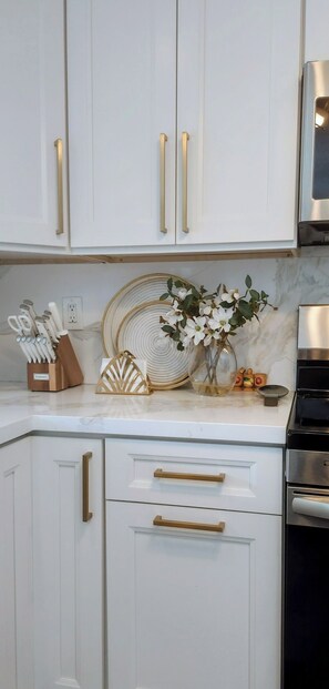 A kitchen with white cabinetry, gold handles, and a stainless steel oven.