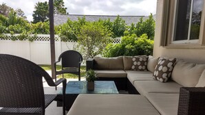 Ein Patio mit einer Korbsitzgruppe, einem Glastisch und einem Stuhl.