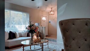 Ein Wohnzimmer mit einer Couch, einem Glastisch, einer dekorativen Vase und einem gepolsterten Sessel.