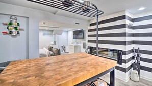 A modern kitchen with a wooden countertop, a hanging rack for bottles, and a striped wall design.