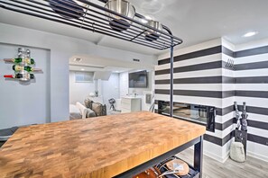 Uma cozinha moderna com bancada de madeira, um suporte suspenso para garrafas e um design de parede listrada.