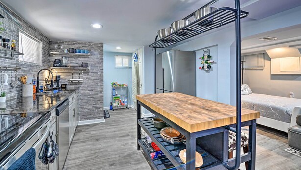 A compact kitchen with a built-in stove, a wooden table, and a hanging pot rack.