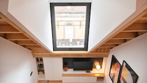 A modern loft with a skylight, wooden beams, a flat-screen TV, and a cozy seating area. - Elegant Downtown Apartment by Vacationy (Porto)
