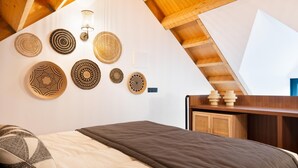 A bedroom with a sloped ceiling, a bed with a patterned pillow, and wall-mounted woven baskets. - Elegant Downtown Apartment by Vacationy (Porto)