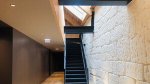 A modern interior with a wooden floor, a black staircase, and a stone wall. - Elegant Downtown Apartment by Vacationy (Porto)