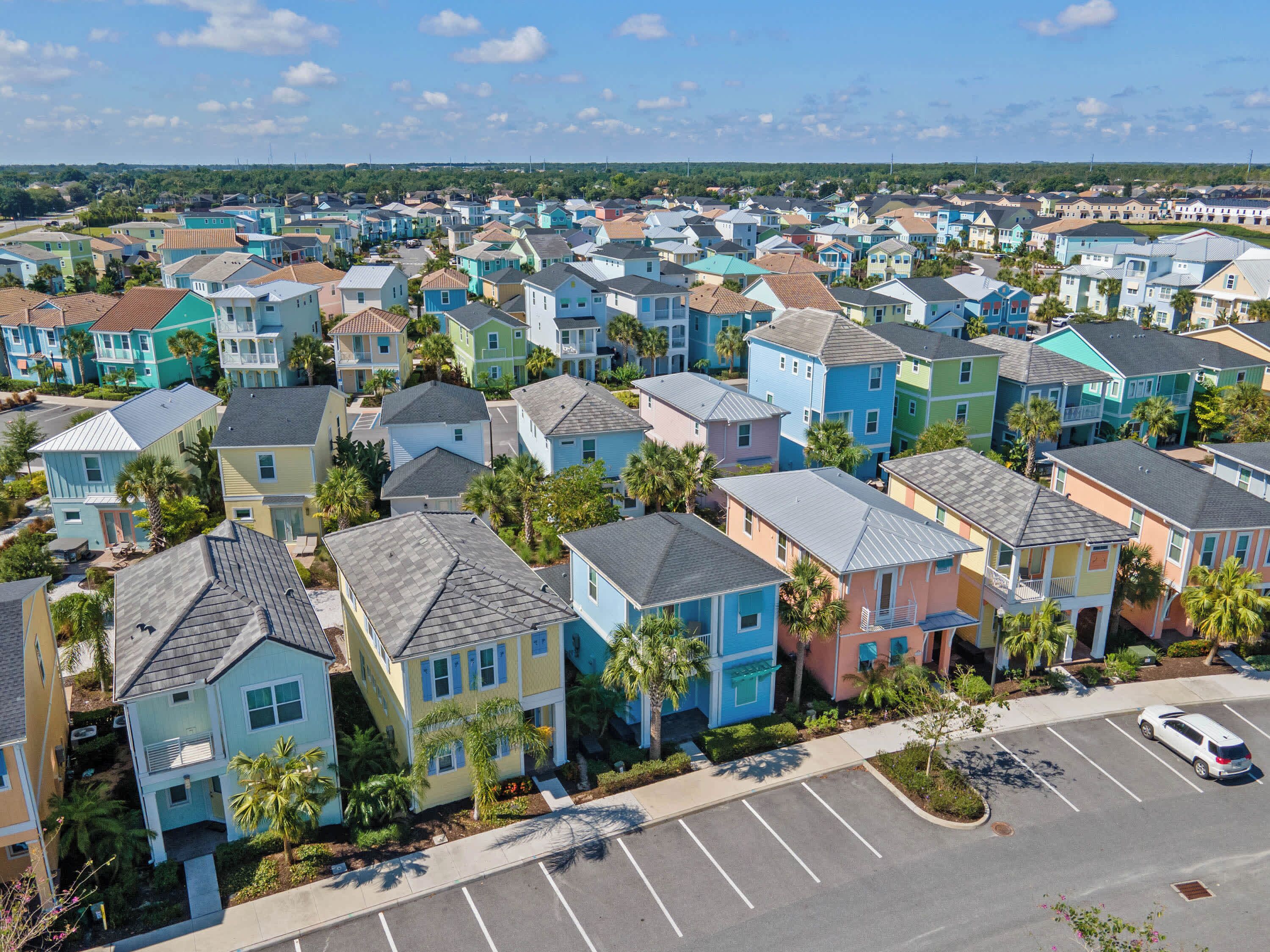 A residential area with colorful houses, a parking lot, and a clear sky.