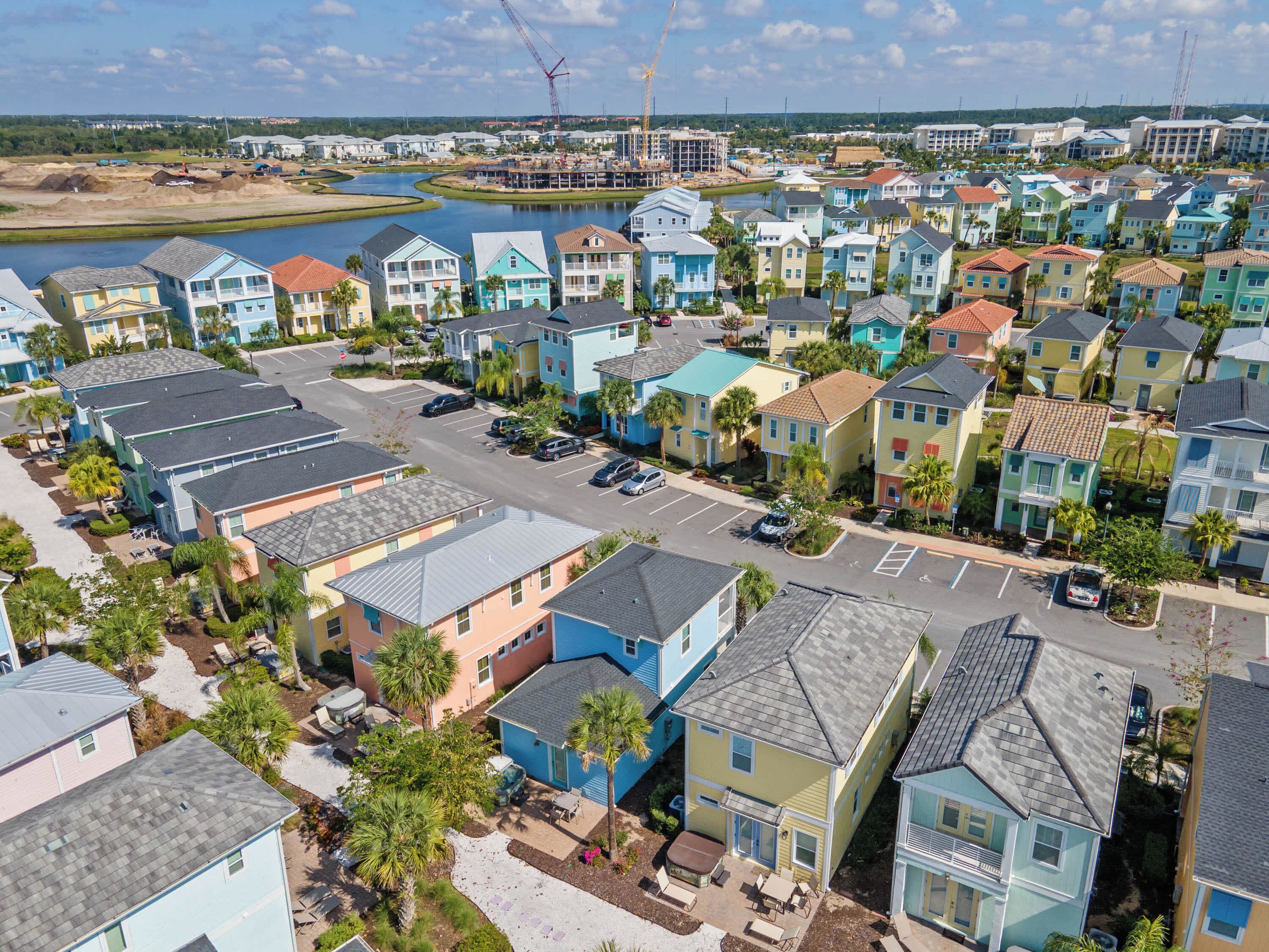 A coastal residential area with colorful houses, a marina, and a construction site in the background.