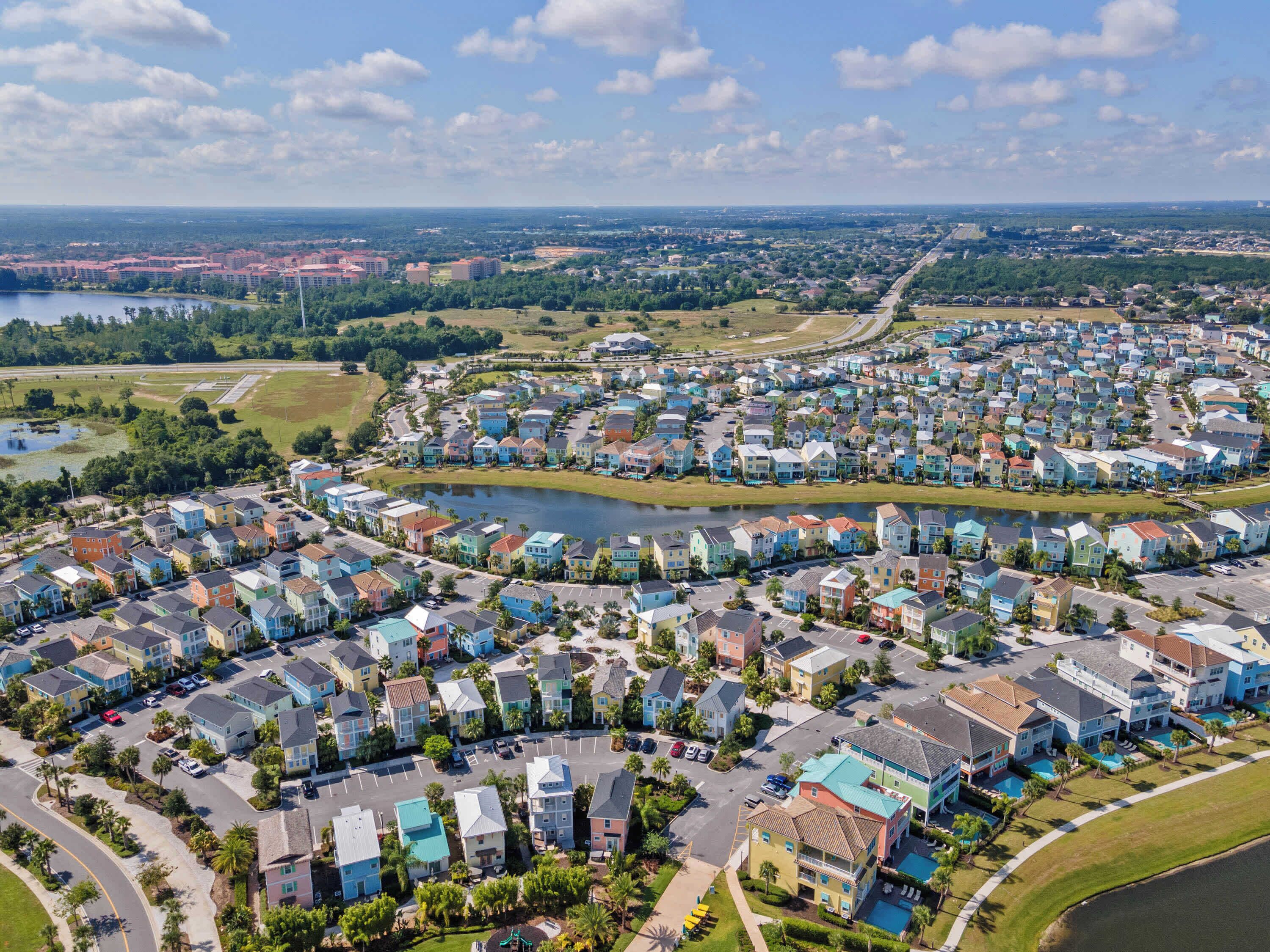 Ett bostadsområde med färgglada hus, en sjö och en avlägsen stadsbild i bakgrunden.