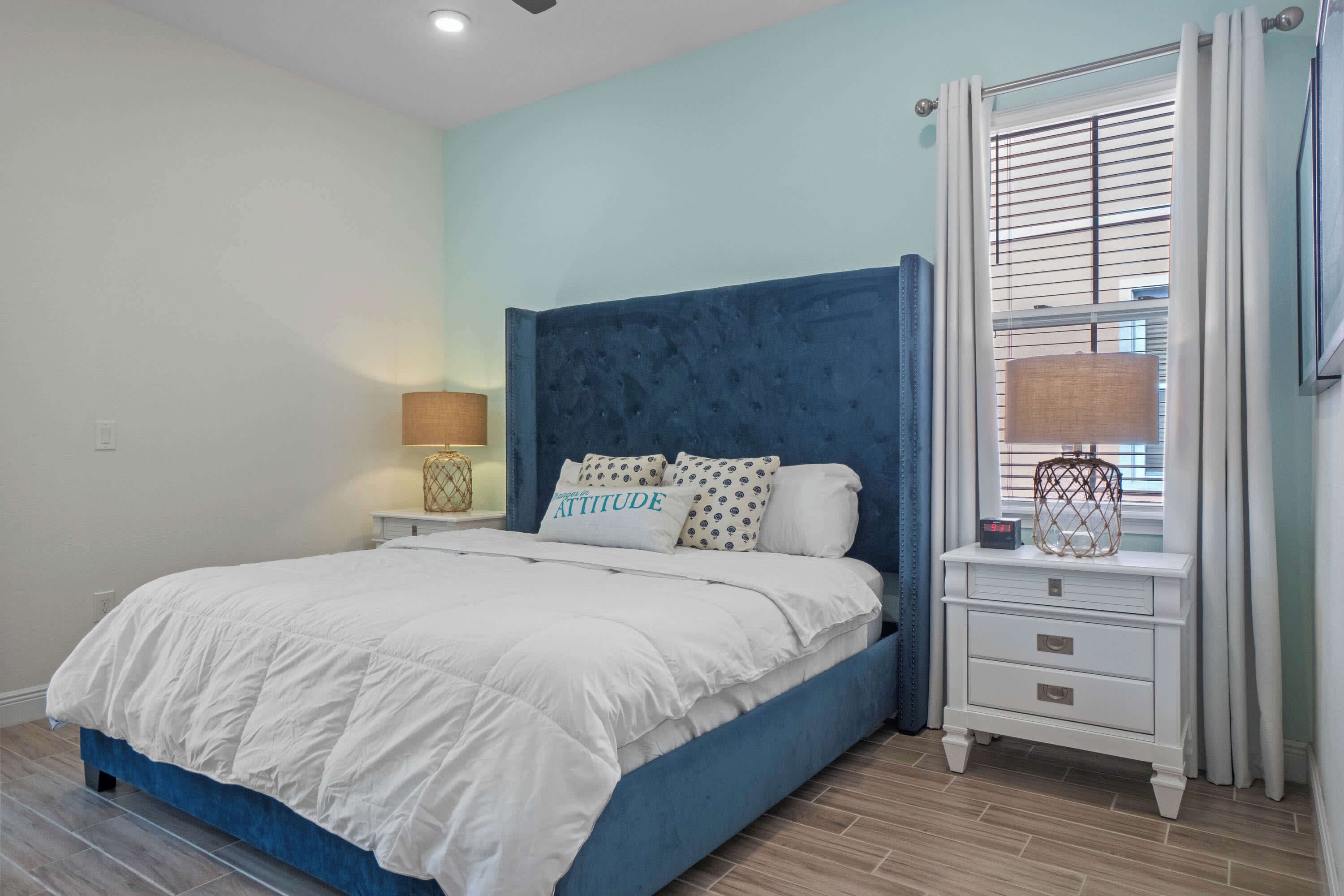 A bedroom with a bed, a nightstand, a lamp, and a window with blinds.