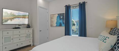 A bedroom with a bed, a dresser, a television, and artwork on the walls.