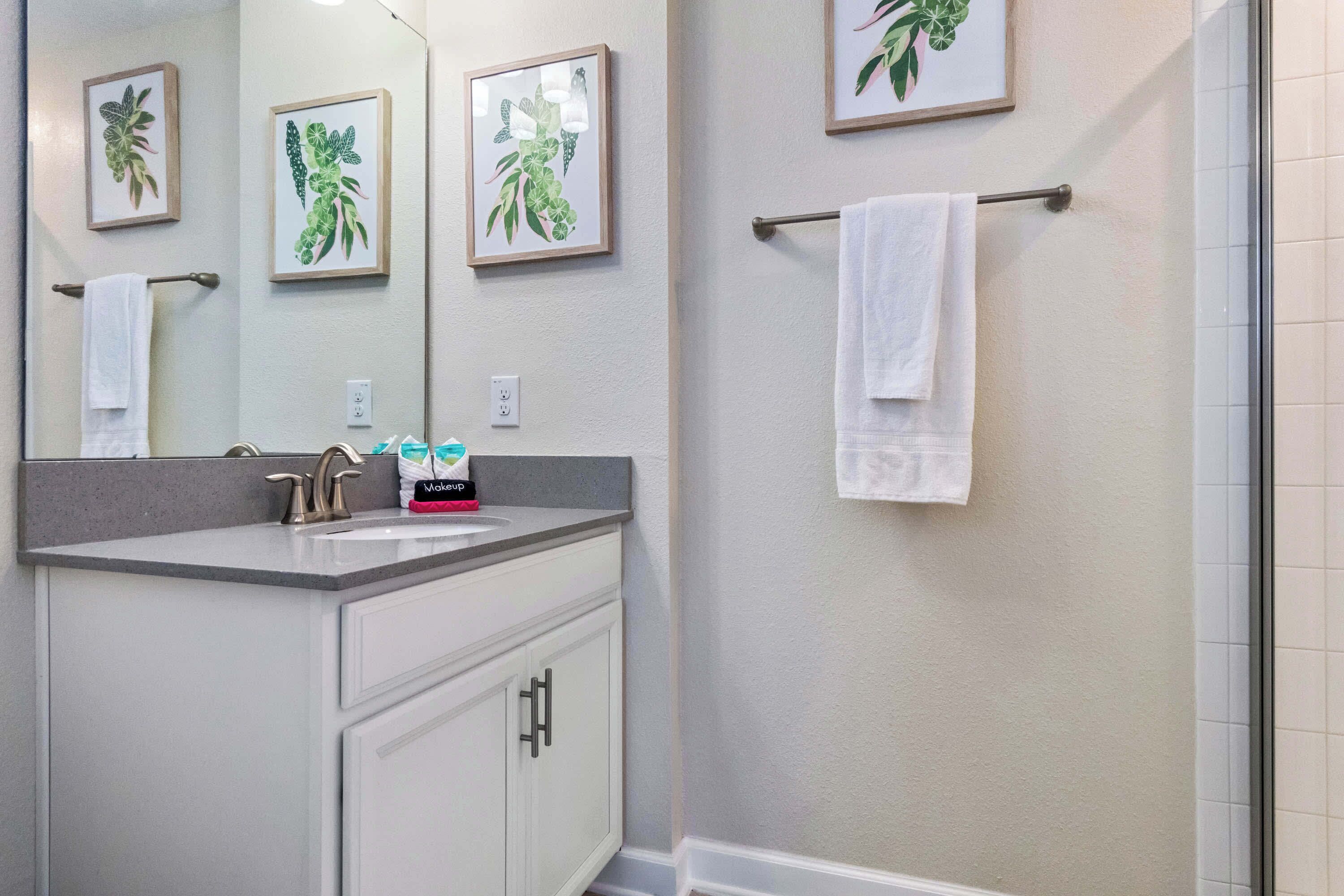 A bathroom with a sink, mirror, and two framed botanical prints on the wall.
