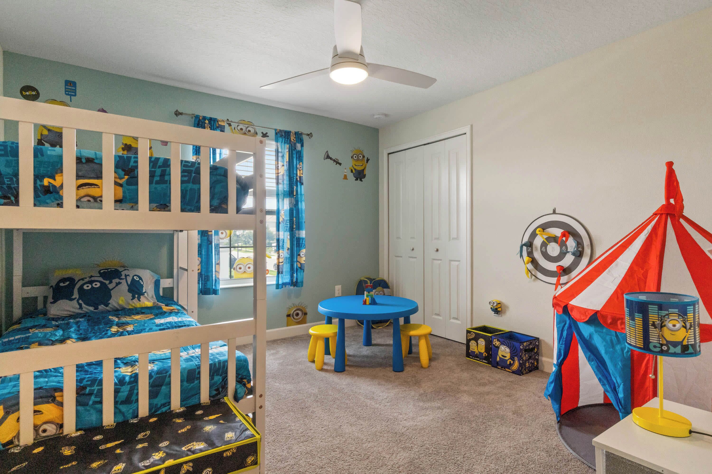 A child's room with bunk beds, a small round table, and a tent decoration.