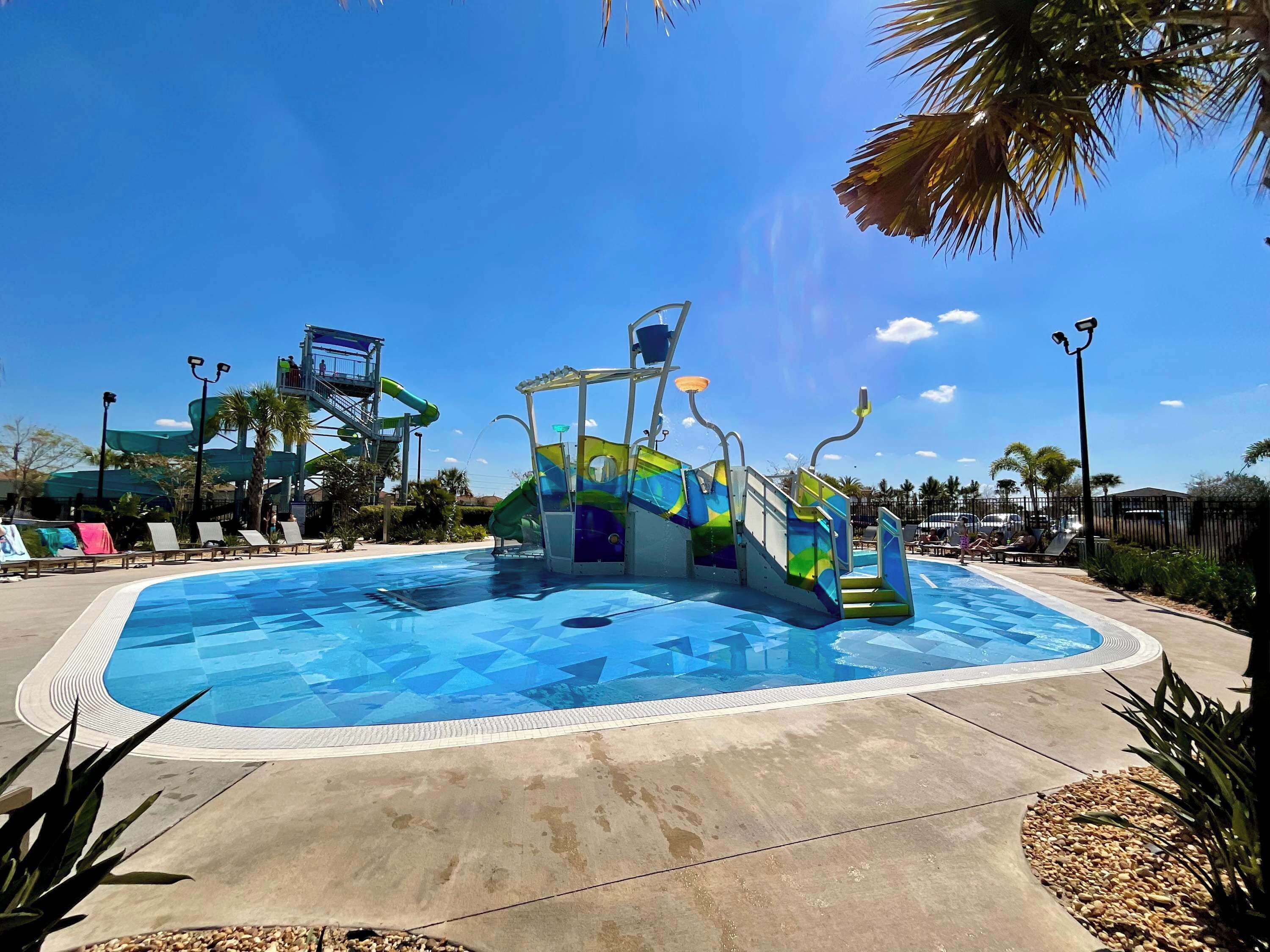 Une piscine avec un toboggan, des chaises longues et des palmiers.